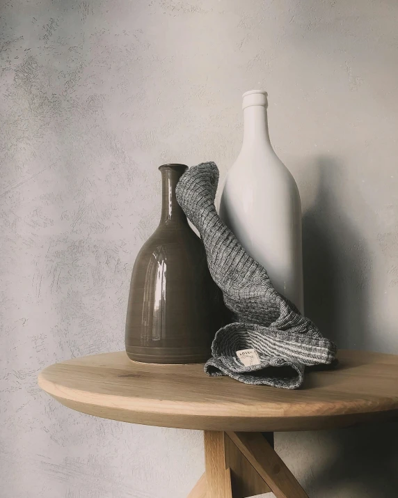 two vases sitting on top of a wooden table, a picture, wearing a grey robe, tweed colour scheme, on kitchen table, product shot