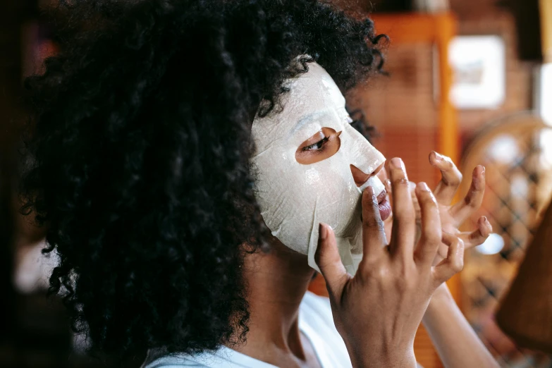 a woman putting a mask on her face, manuka, grey, fan favorite, [ organic