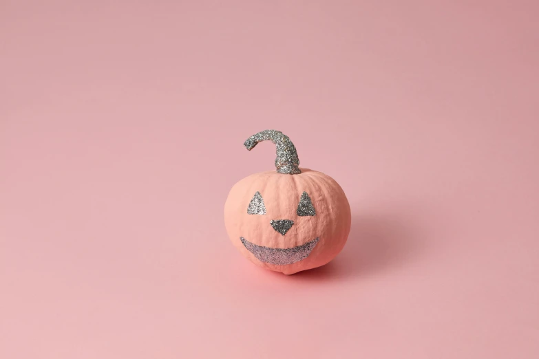 a small pumpkin sitting on top of a pink surface, glitter sticker, textured base ; product photos, spooked, pink