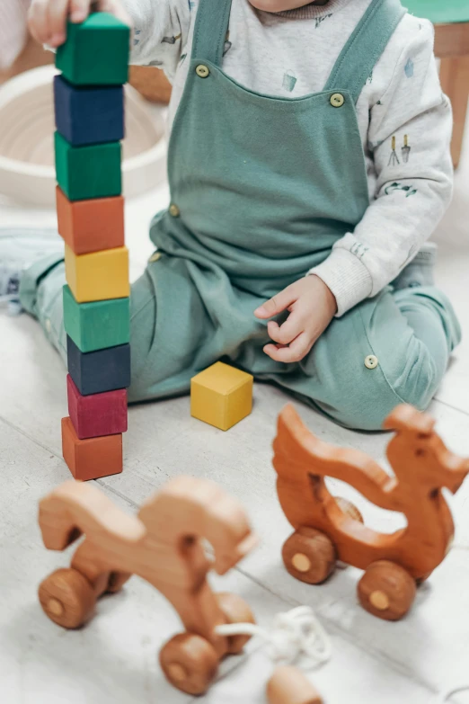 a baby sitting on the floor playing with wooden blocks, pexels contest winner, visual art, solid coloured shapes, islamic, zoomed in, towering above a small person