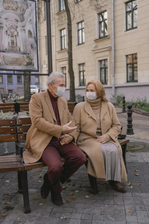 a couple of people that are sitting on a bench, wearing a mask, brown clothes, looking old, healthcare