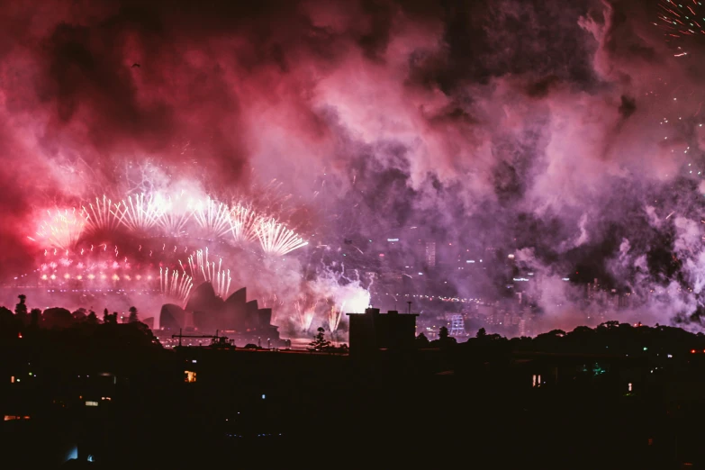 fireworks light up the night sky over a city, happening, purple and scarlet colours, smokey cannons, profile image, a wide shot