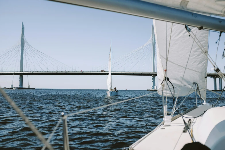 a sailboat in the water with a bridge in the background, pexels contest winner, happening, in style of heikala, views to the ocean, tournament, close together