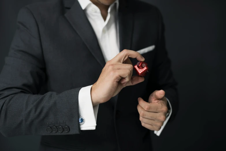 a close up of a person in a suit holding a cell phone, an album cover, inspired by Ernő Rubik, unsplash, crimson led, doing an elegant pose, dice, black tie