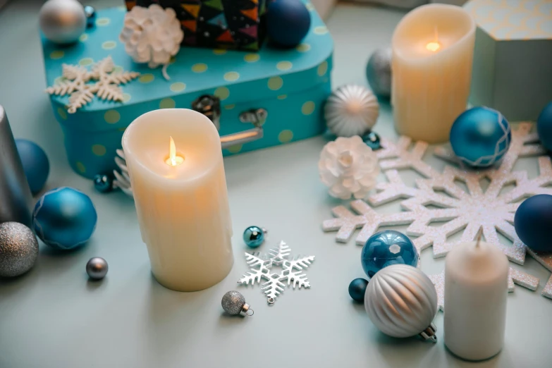 a group of candles sitting on top of a table, a still life, trending on pexels, snowflakes, background image, light blue, a high angle shot