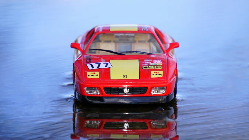 a toy car sitting on top of a body of water, unsplash, photorealism, ferrari, ilustration, rally driving photo, glossy plastic