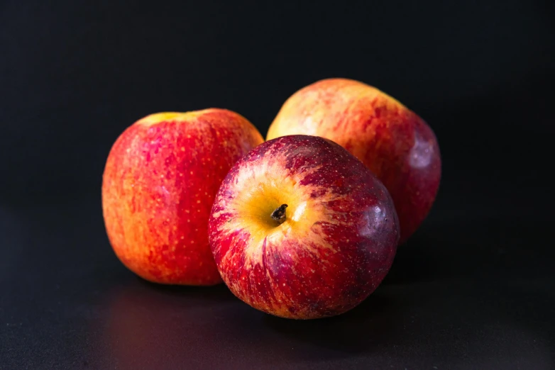 two red apples sitting next to each other on a black surface, by Matthias Stom, pexels, fan favorite, multicoloured, full body close-up shot, miniature product photo