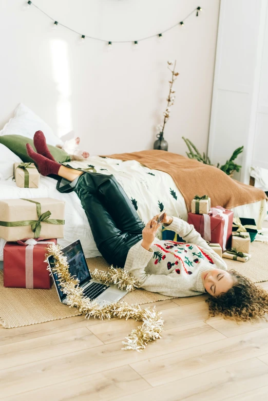 a woman laying on the floor surrounded by presents, by Julia Pishtar, full device, winter vibes, casually dressed, gif