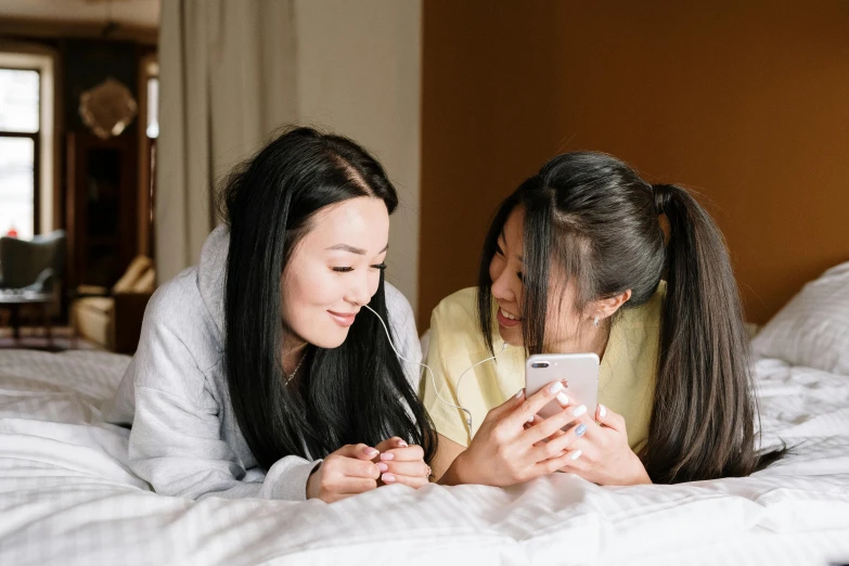 a couple of women laying on top of a bed, a photo, trending on pexels, girl making a phone call, chinese, avatar image