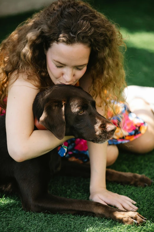 a woman sitting on the grass with a dog