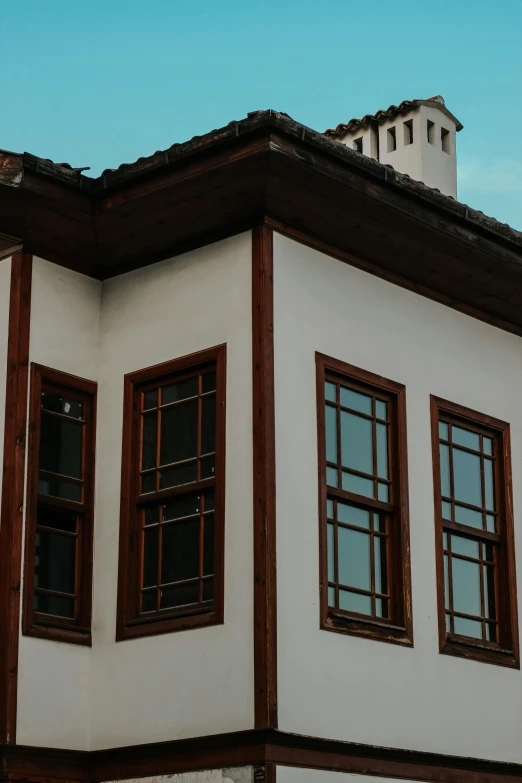 a white and brown building with a clock on top of it, inspired by Osman Hamdi Bey, pexels contest winner, arts and crafts movement, bay window, turkey, 1 5 9 5, black windows