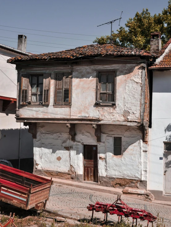 a truck parked on the side of a road next to a building, an album cover, inspired by Constantine Andreou, pexels contest winner, renaissance, white buildings with red roofs, aged and weathered, panorama view, front and side elevation