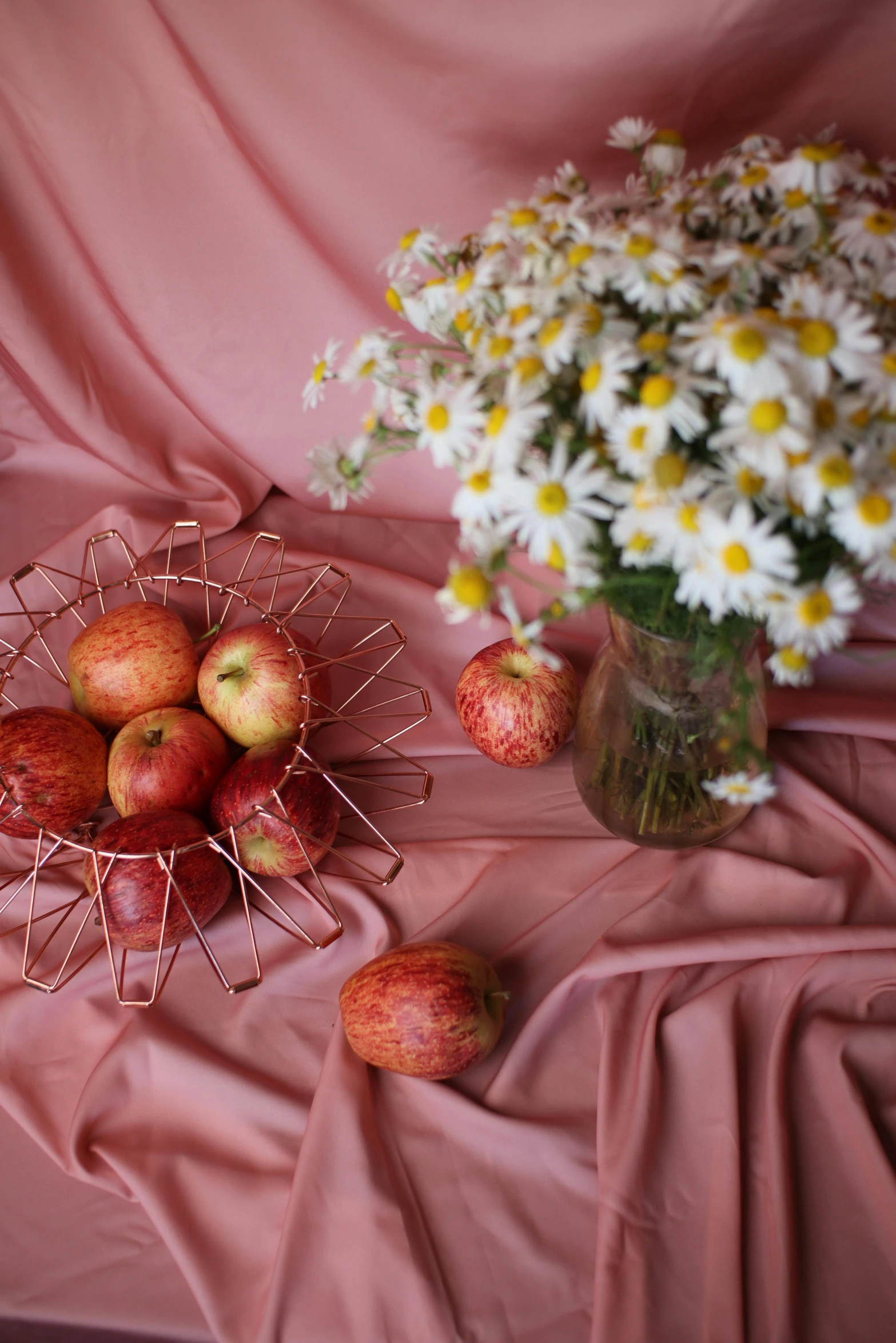 a bunch of apples sitting on top of a table, a still life, inspired by Elsa Bleda, shutterstock contest winner, daisies and poppies, flowing pink-colored silk, designed for cozy aesthetics!, ((still life))