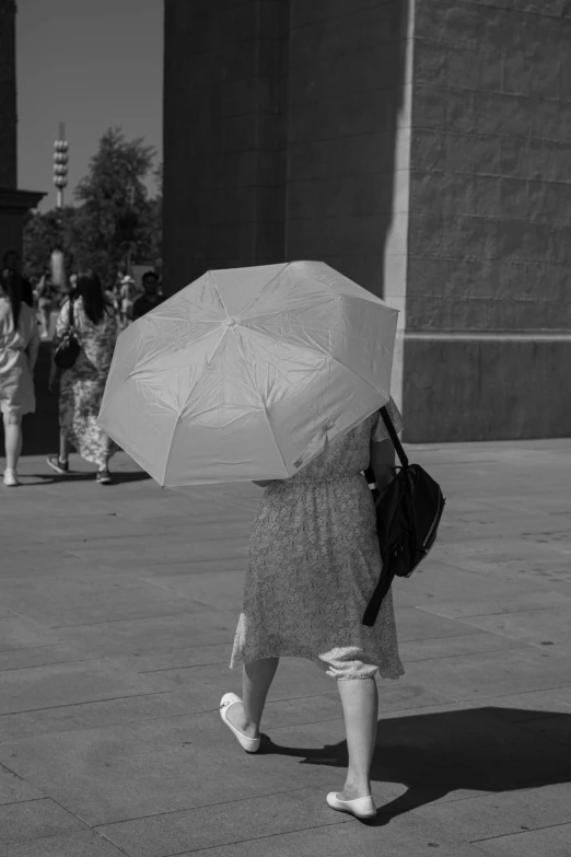 a black and white photo of a woman holding an umbrella, unsplash, hyperrealism, hot summer day, pedestrians, white in color, very poor quality of photography