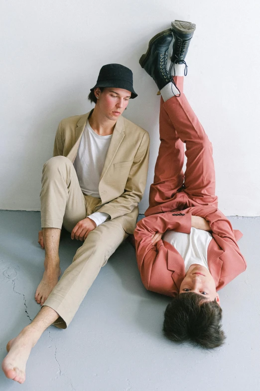 a couple of men laying on top of each other, an album cover, unsplash, tan suit, baggy pants, boyish, at a fashion shoot