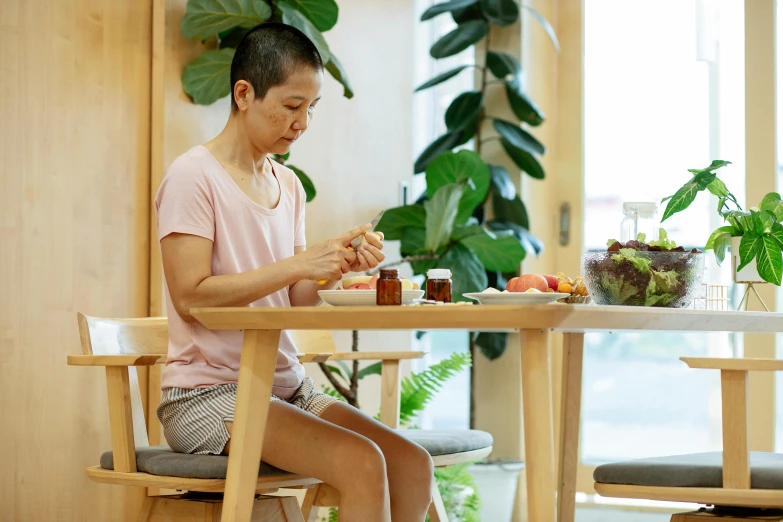 a woman sitting at a table eating food, by Jang Seung-eop, manuka, maintenance, on wooden table, easygoing