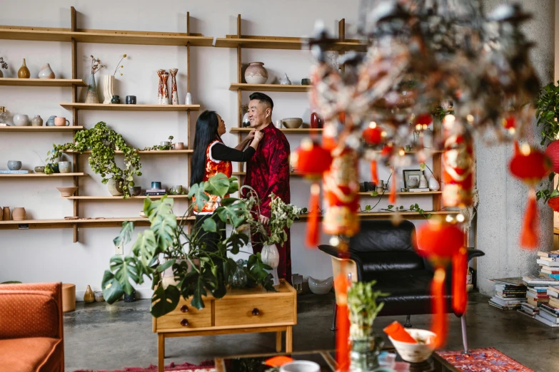 a couple of people that are standing in a room, by Julia Pishtar, pexels contest winner, cloisonnism, lush plants and flowers, accents of red, inspect in inventory image, joy ang