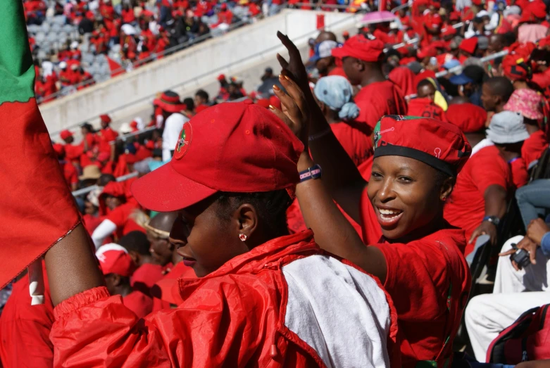 a group of people that are standing in a stadium, by Hubert van Ravesteyn, hurufiyya, wearing red attire, cheering, 15081959 21121991 01012000 4k, red cap with a capital m