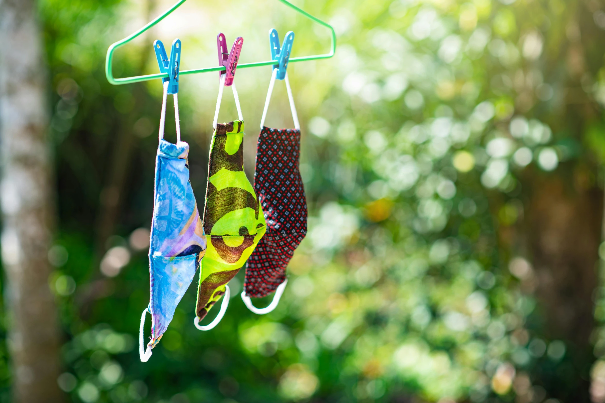 a pair of socks hanging from a clothes hanger, by Julia Pishtar, process art, green facemask, bright summer day, family friendly, bandanas