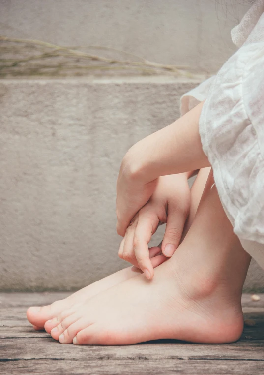 a close up of a person sitting on a wooden floor, inspired by Elsa Bleda, unsplash, renaissance, porcelain skin ”, giant kicking foot, bumps, standing on a rock