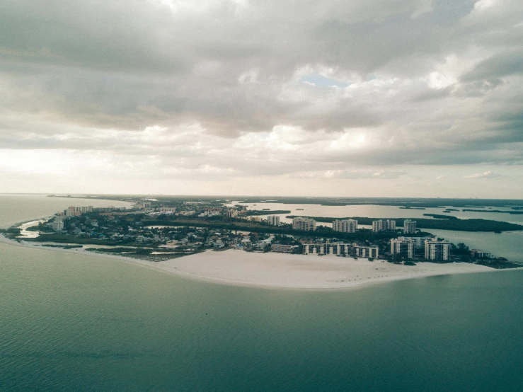 an island in the middle of a body of water, by Ryan Pancoast, pexels contest winner, the emerald coast, white pale concrete city, clouds around, 3 / 4 wide shot