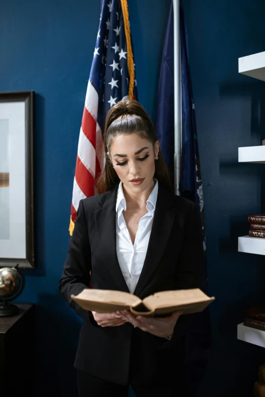 a woman in a business suit reading a book, a portrait, pexels contest winner, u.s. national security advisor, handsome girl, patriotism, standing in corner of room