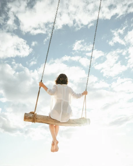 a woman in a white dress is sitting on a swing, pexels contest winner, sunny sky, myself, lgbtq, al fresco