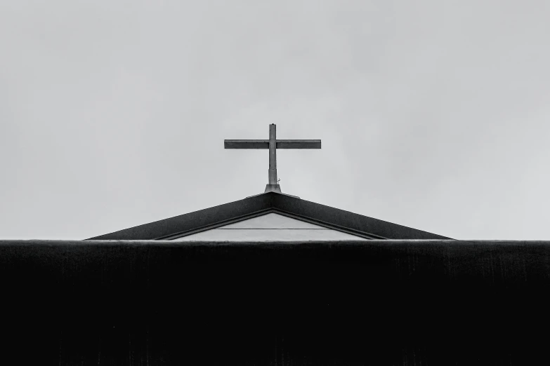 a black and white photo of a cross on top of a building, by Daniel Lieske, pexels, priest, high quality upload, black roof, ad image