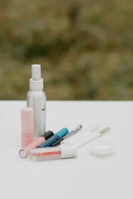 a couple of bottles sitting on top of a table, putting makeup on, fine point pen, one disassembled, soft blue and pink tints