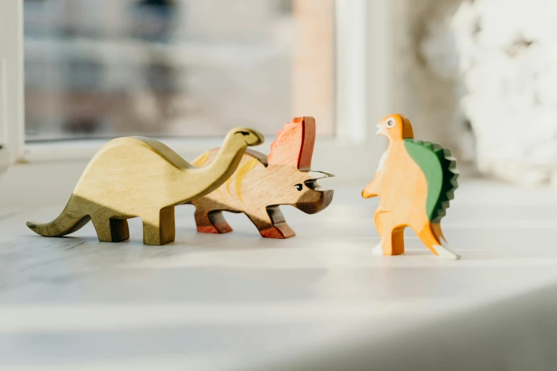 a couple of wooden dinosaurs standing next to each other, a jigsaw puzzle, by Liza Donnelly, trending on unsplash, vignette of windowsill, three animals, product design shot, slightly turned to the right