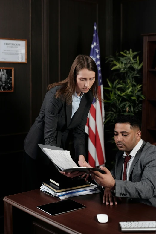 a couple of people that are sitting at a desk, defense attorney, he is holding a large book, girl in suit, patriotism