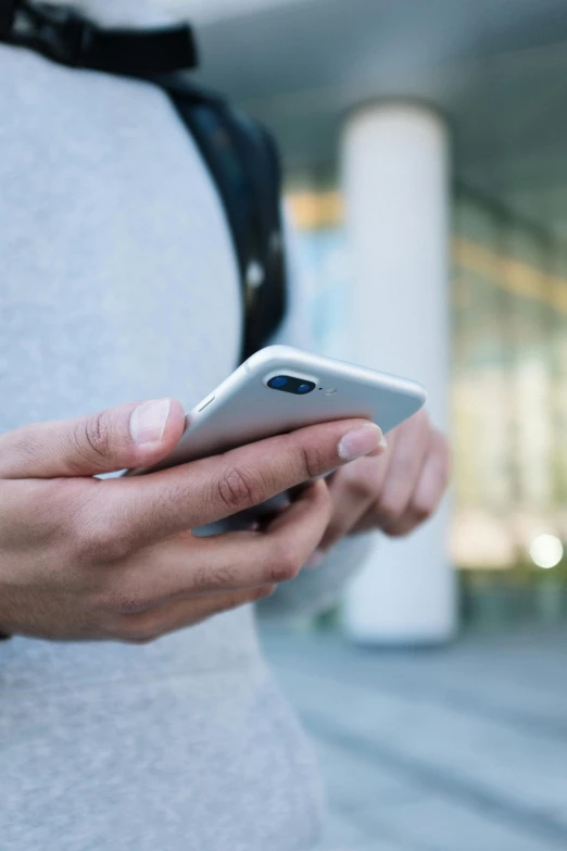 a close up of a person holding a cell phone, by Dan Content, square, grey, university, outside