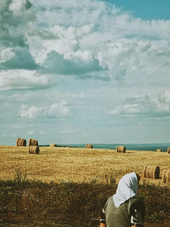 a person sitting on a bench in a field, an album cover, by Lucia Peka, unsplash contest winner, surrealism, field of hay, vereshchagin, praying, instagram story