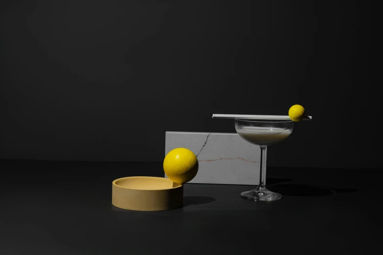 a martini glass sitting on top of a table next to a lemon, a still life, by Ndoc Martini, conceptual art, porcelain forcefield, float, mono-yellow, made of liquid metal and marble