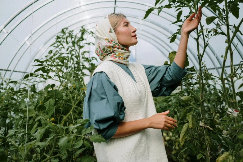 a woman picking tomatoes in a greenhouse, inspired by Elsa Beskow, pexels contest winner, renaissance, white hijab, model is wearing techtical vest, photoshoot for skincare brand, portrait of tall