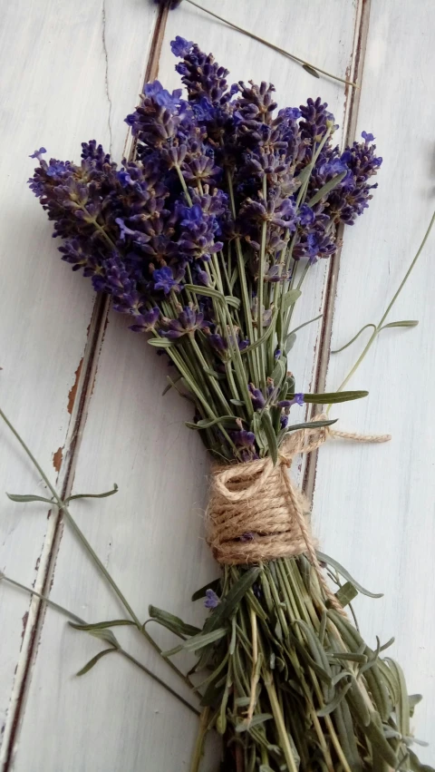 a bunch of lavender sitting on top of a wooden table, unsplash, door, mediumslateblue flowers, vintage photo, made of glazed