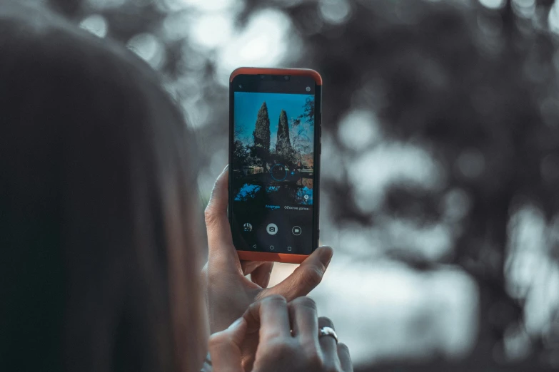 a woman taking a picture with her cell phone, a picture, trending on pexels, towering over the camera, shot from a distance, android close to camera, low colour