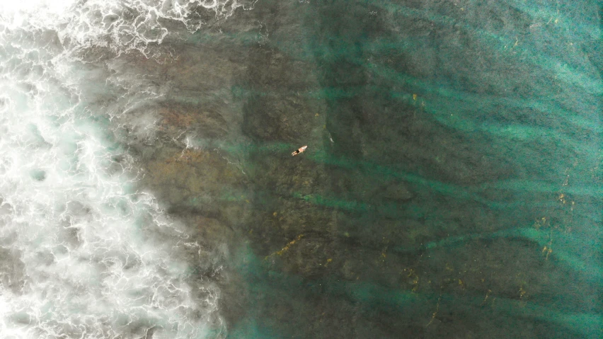 a person riding a surfboard on top of a body of water, by Daniel Lieske, pexels contest winner, minimalism, reefs, oil spill, birdseye view, manly