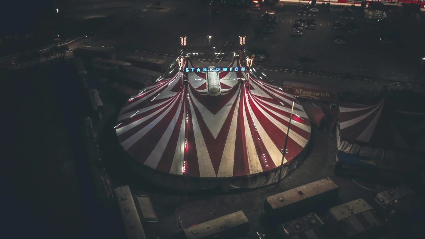 an aerial view of a circus at night, a colorized photo, unsplash contest winner, star roof, striped, symmetrical outpost, clown