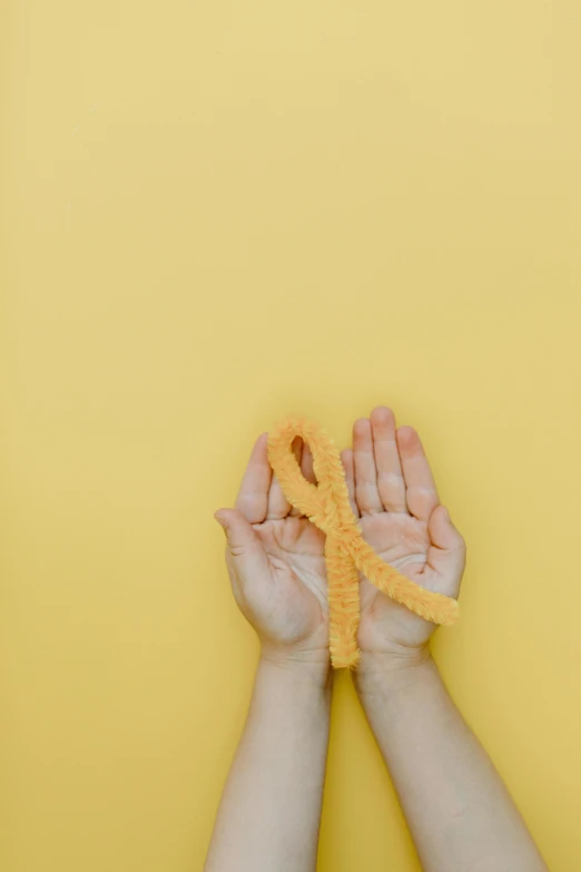 a person holding a yellow ribbon in their hands, by Carey Morris, hurufiyya, oesophagus, orange, virus, relief