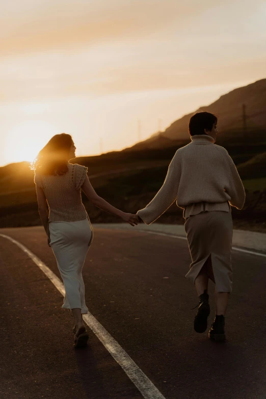 a man and woman walking down a road holding hands, trending on pexels, renaissance, low sunset, lesbians, hills, katey truhn