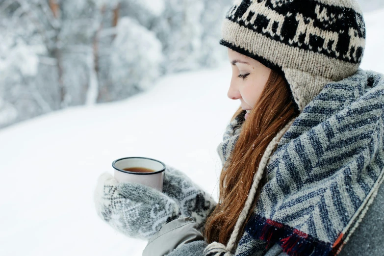 a woman sitting in the snow holding a cup of coffee, inspired by Louisa Matthíasdóttir, pexels contest winner, woman with braided brown hair, tea, woman with hat, youtube thumbnail