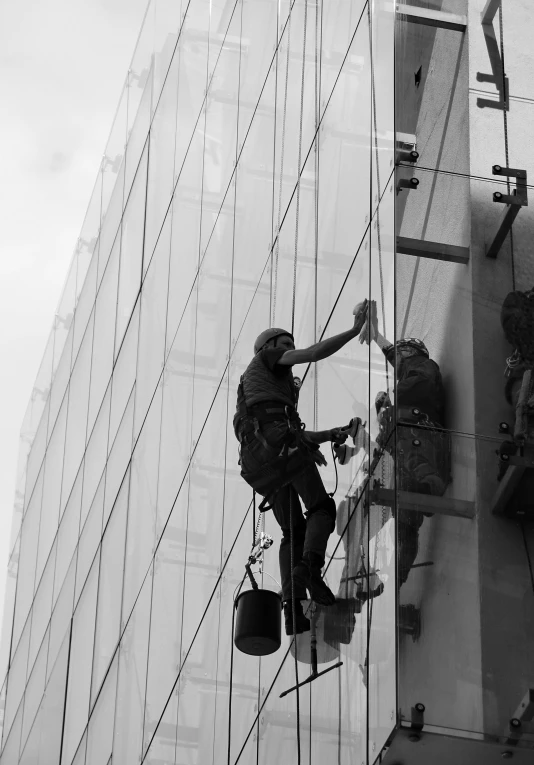 a black and white photo of a window washer, repairing the other one, in 2 0 1 5, performance, glazed