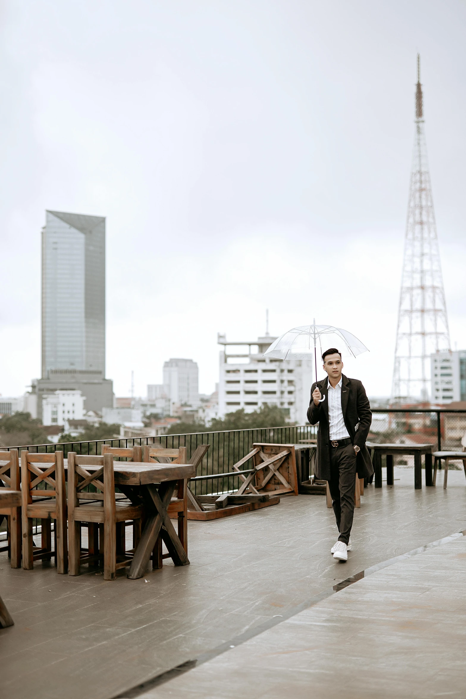 a man walking down a sidewalk holding an umbrella, standing on a skyscraper rooftop, dang my linh, at the terrace, wearing a fancy jacket