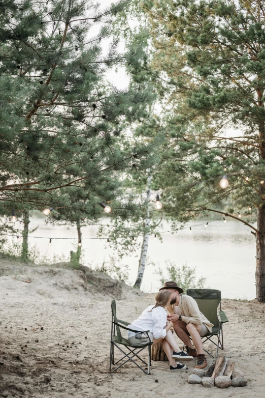 a couple of people that are sitting in a chair, by Grytė Pintukaitė, unsplash, romanticism, glamping, on the sand, low quality photo, romantic greenery