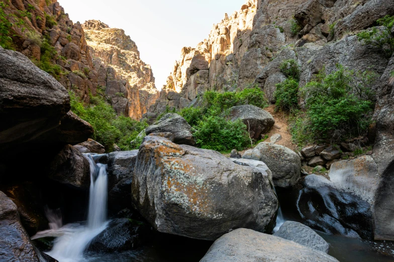 a small waterfall in the middle of a canyon, unsplash, hurufiyya, boulders, 2 0 0 0's photo