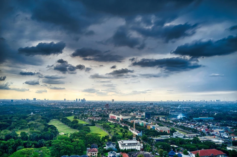 a view of a city from the top of a building, by Basuki Abdullah, pexels contest winner, sumatraism, stormclouds, manila, ultrawide landscape, grass field surrounding the city