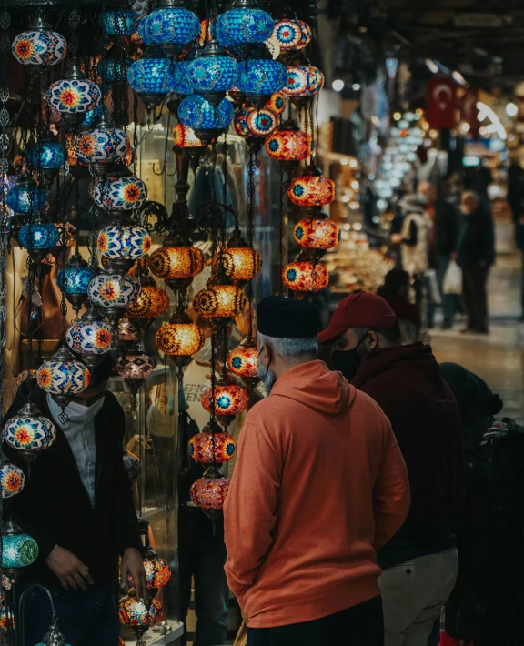 a group of people standing in front of a store, trending on pexels, art nouveau, colorful lanterns, turkish and russian, hanging out with orbs, market setting