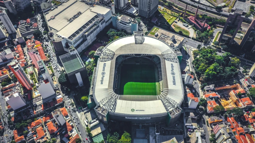 an aerial view of a soccer stadium in a city, by Luis Miranda, 🚿🗝📝, green square, exterior shot, post processed