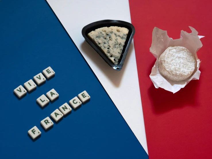 a piece of cheese sitting on top of a table, an album cover, inspired by François Louis Thomas Francia, trending on unsplash, figuration libre, french flag, fresh bakeries in the background, blue and white, hidden message